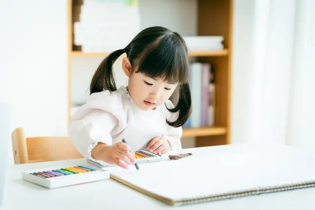 ダイニングテーブルでお絵描きをする女の子