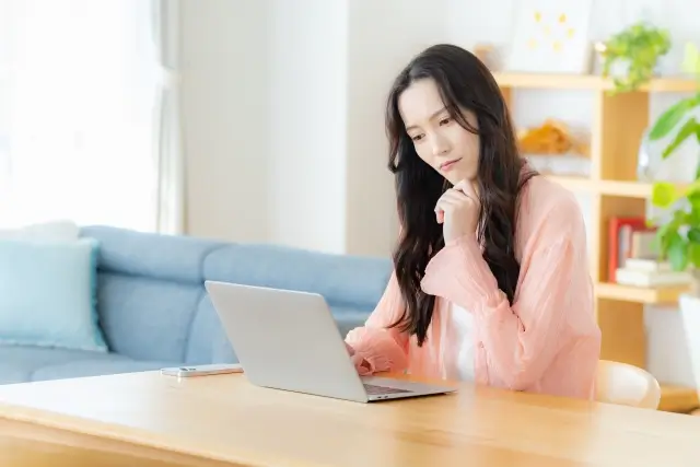 ダイニングテーブルでパソコンを操作する女性